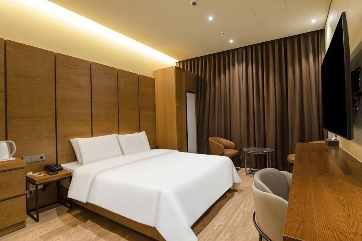 Een hotelkamer met een groot bed, een bureau met stoel, een televisie en een kleine tafel met stoel.