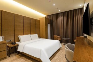Una habitación de hotel con una cama grande, un escritorio con una silla, un televisor y una pequeña mesa con una silla.