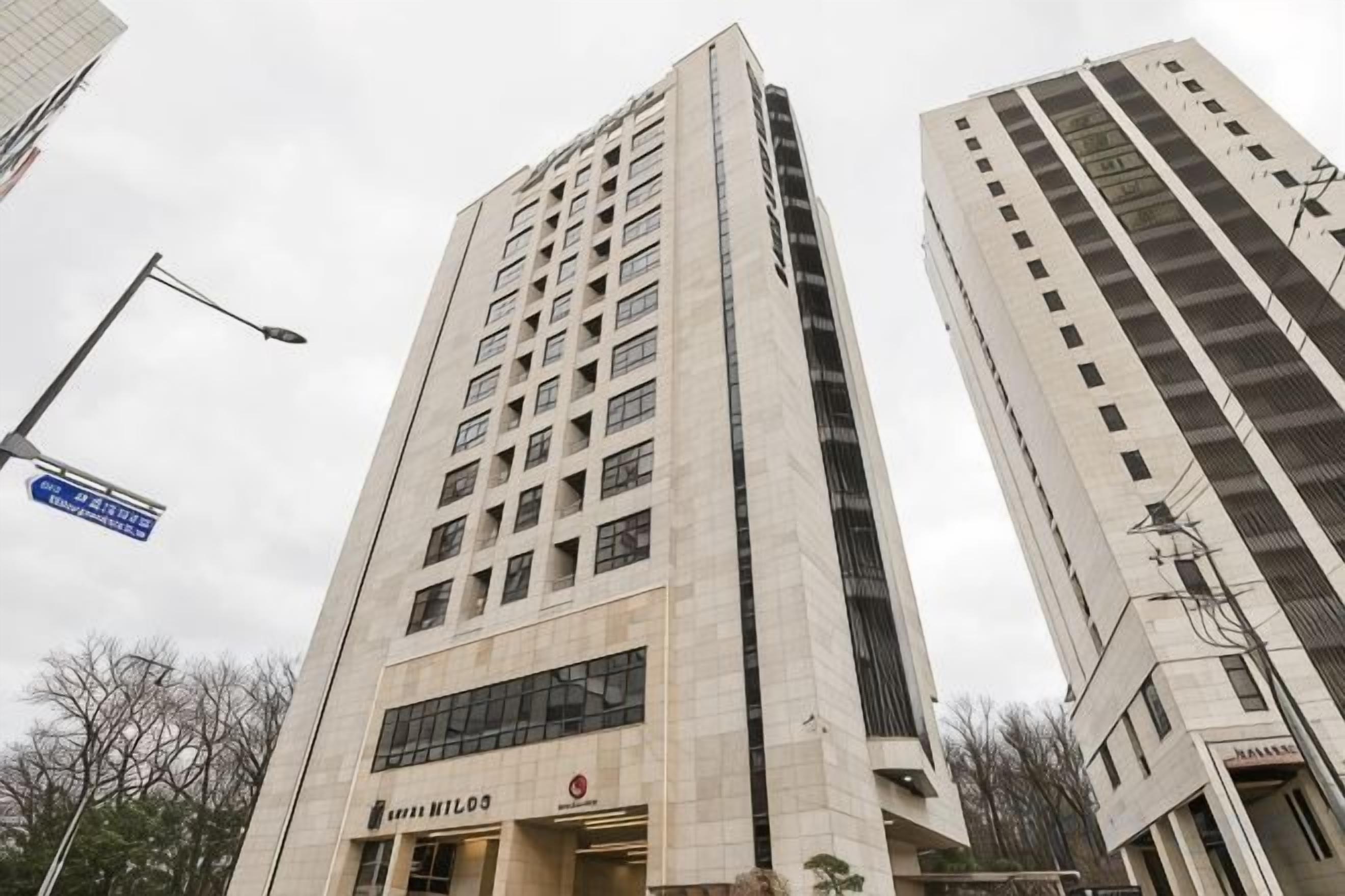 Un edificio alto con varios pisos y una entrada destacada.