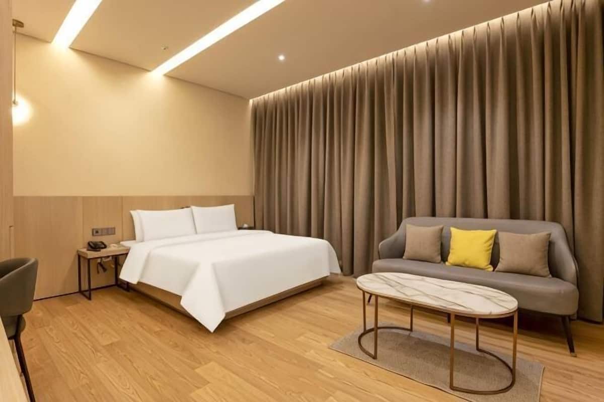 Een hotelkamer met een bed, een bank, een salontafel en een gordijn.