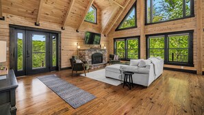 A spacious room with a fireplace, large windows, and a cozy seating area. - Arch Fun Cabin - Modern Cabin w/ Hot Tub, Games & Views (Stanton)