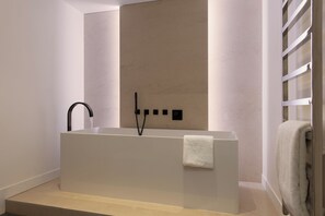 A modern bathroom with a rectangular bathtub, a black faucet, and a towel rack. - HIGHSTAY - Luxury Serviced Apartment - Saint-Germain (Paris)