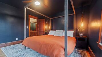 Quarto com cama, mesa de cabeceira, ventilador de teto e luz noturna.