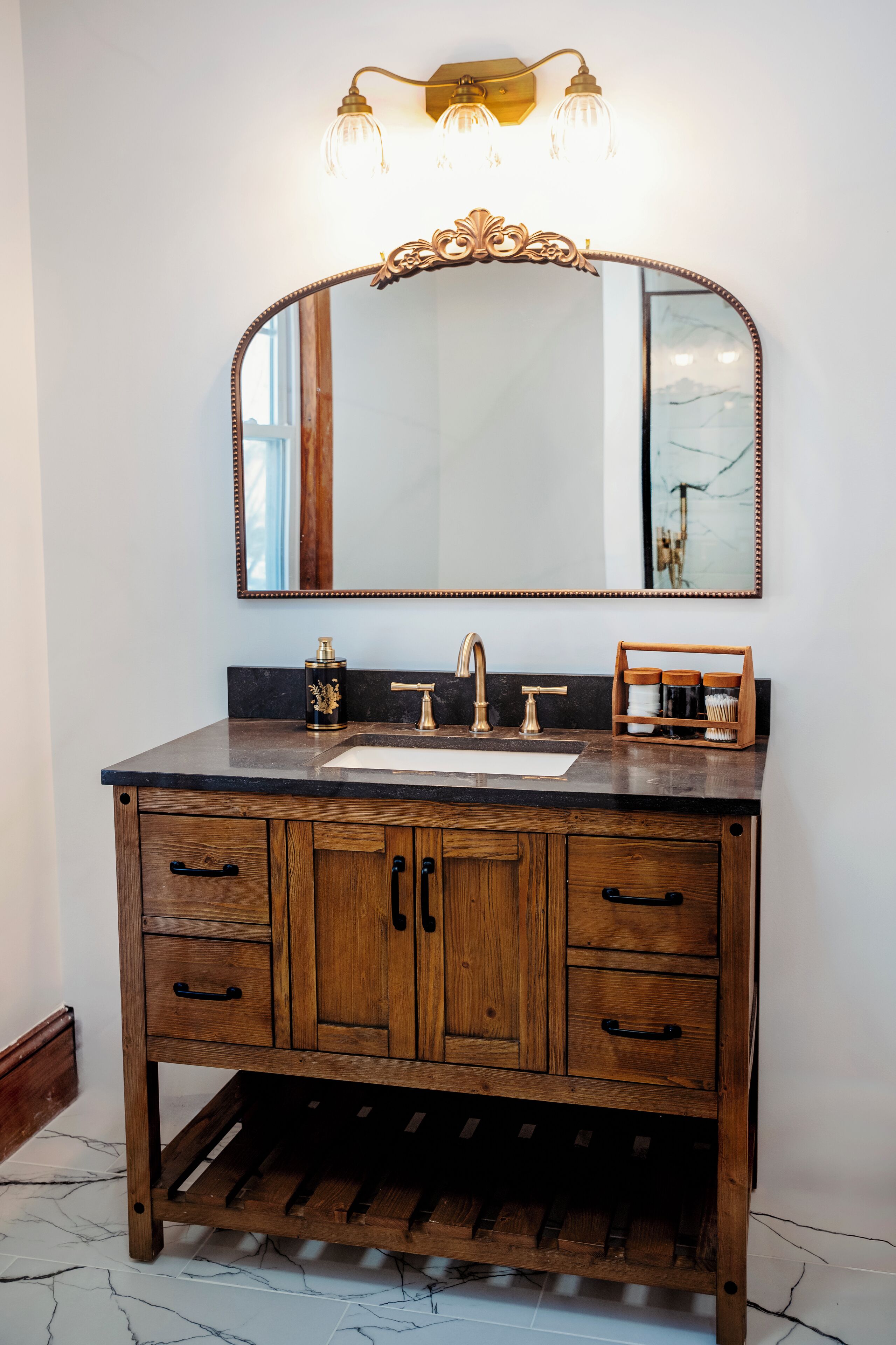 A wooden vanity with a mirror, a sink, and a wine rack below.