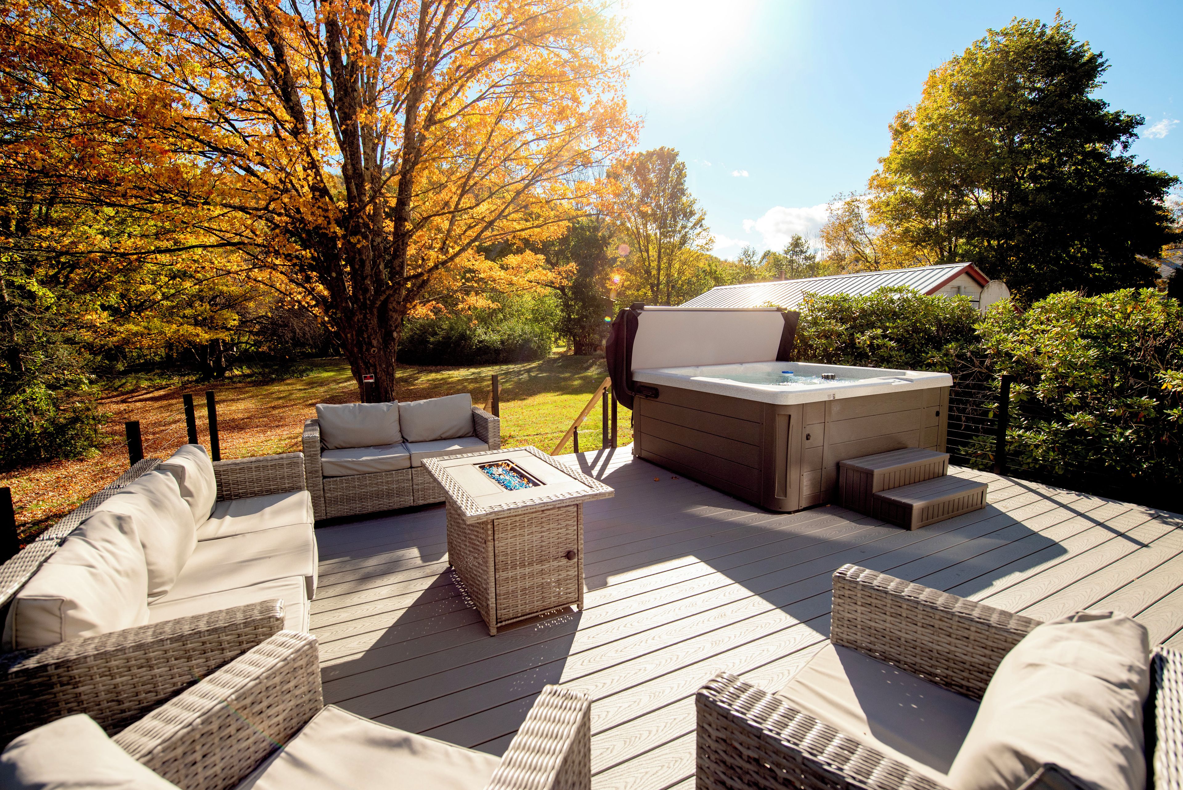 An outdoor deck with wicker furniture and a hot tub.