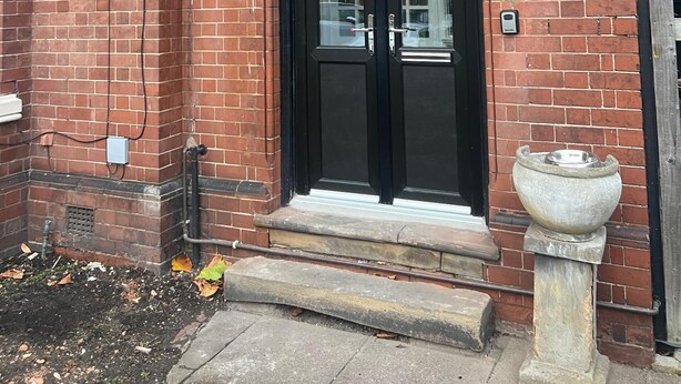 A brick building with a black double door and a small porch area.