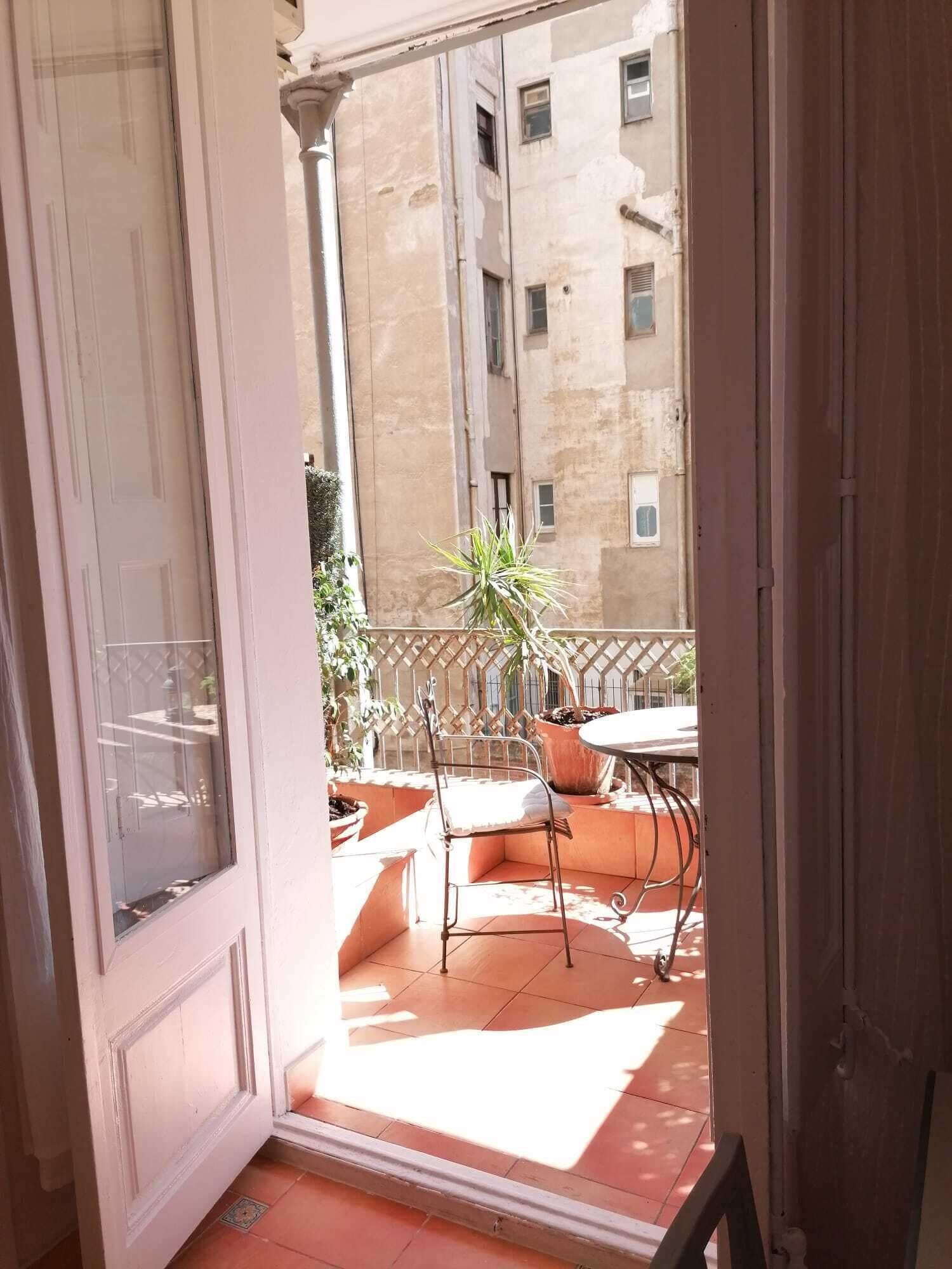 Un balcon avec une chaise en métal, une petite table et des plantes en pot.