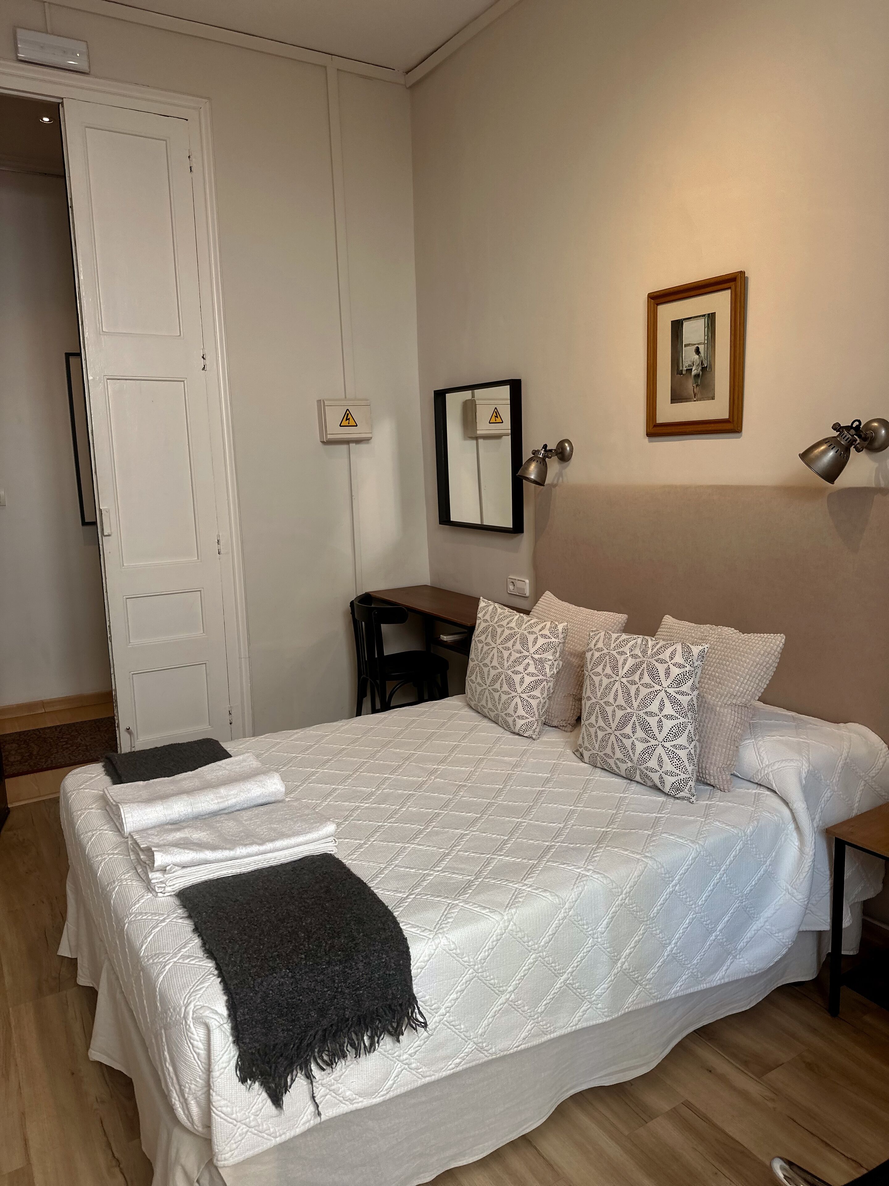 A neatly made bed with patterned pillows, a bedside lamp, and a framed picture on the wall.