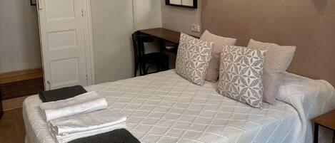 A neatly made bed with patterned pillows, a bedside lamp, and a framed picture on the wall.