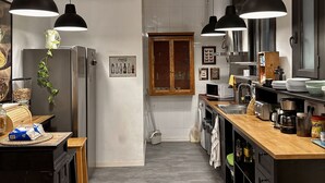 Une cuisine moderne avec des suspensions noires, un plan de travail en bois et un réfrigérateur en acier inoxydable.