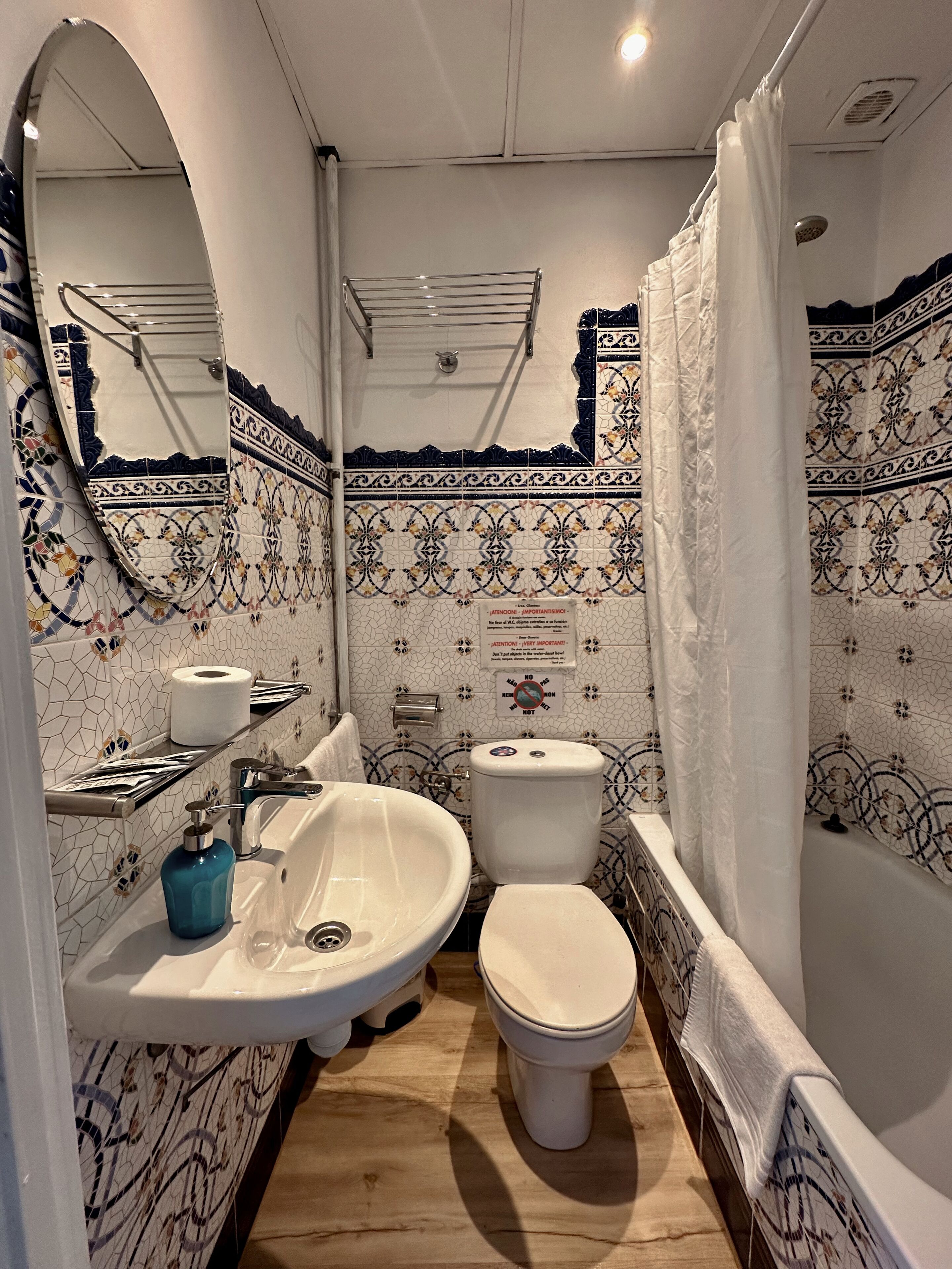 A bathroom with a sink, toilet, and bathtub. There are decorative tiles on the walls and a shower curtain.