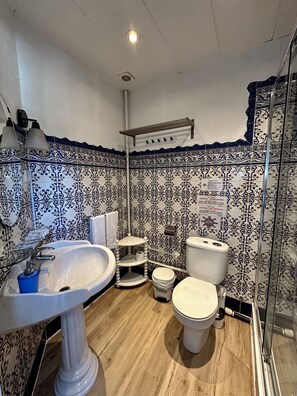 Ein Badezimmer mit einem weißen Waschtisch, einer Toilette und einer Duschkabine.