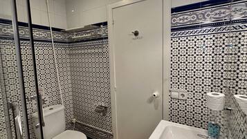 A bathroom with a toilet, a sink, and a shower area.
