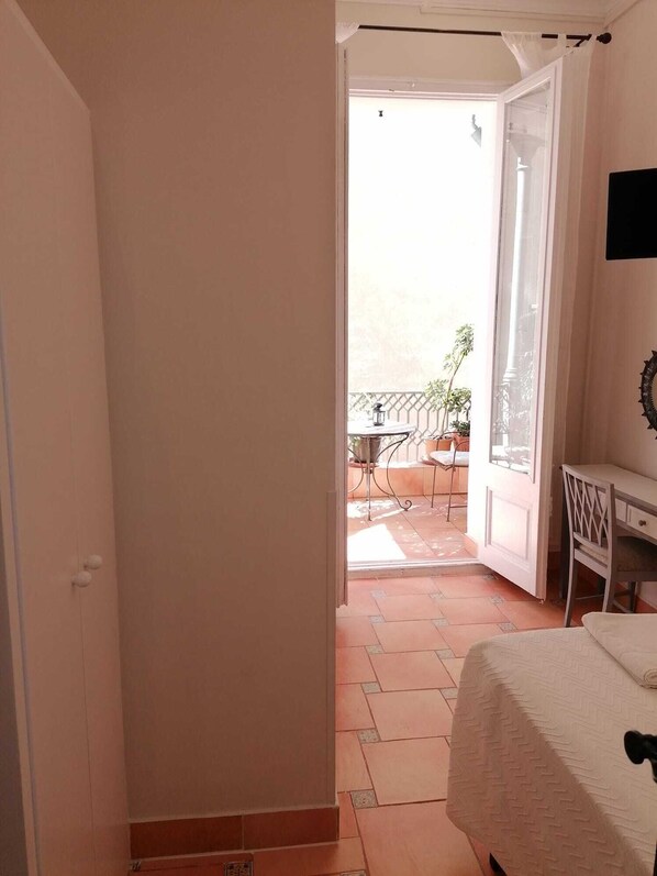 Una habitación con cama, escritorio y vistas a un patio exterior con mesa y sillas.