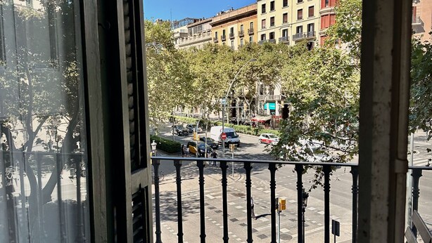 Un balcon donnant sur une rue de la ville, avec une table et une chaise.
