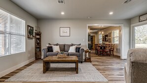 Ein geräumiges Wohnzimmer mit einer großen Couch, einem Couchtisch und einem Essbereich mit Stühlen und einem Tisch.