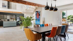 Ein geräumiger Essbereich mit großem Tisch und bunten Stühlen, eine Küche mit modernem Design sowie eine Treppe, die zu einer oberen Ebene führt.