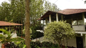 A two-story building with a tiled roof, surrounded by lush greenery and trees. - RAJ VILLAS (Chikkamagaluru)