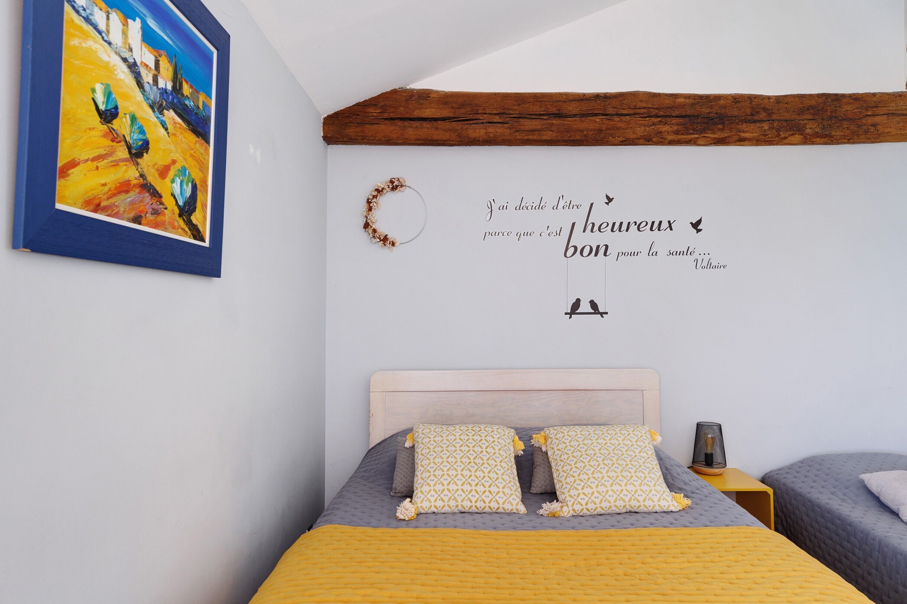 Ein Schlafzimmer mit einem Bett, einem Nachttisch, einer Wanddekoration und einem Gemälde.