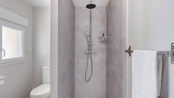 Een badkamer met een douche, toilet en een raam.
