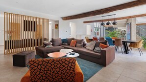 Una sala moderna con un sofá modular, otomanas y un comedor con sillas y una mesa.