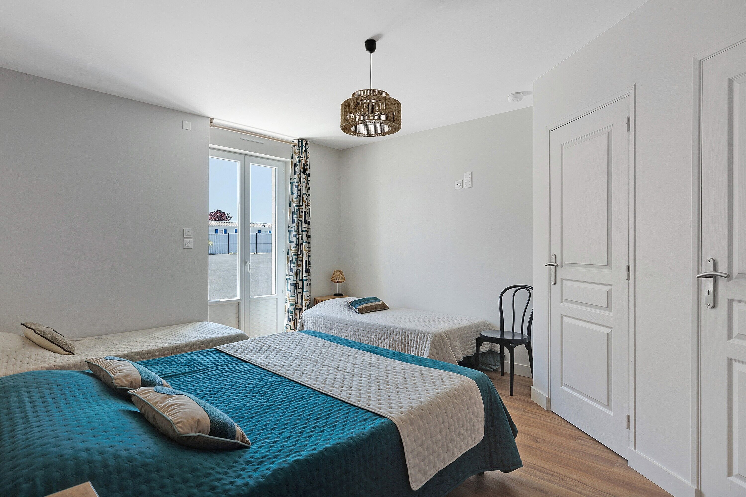 A bedroom with two beds, a door, and a window.