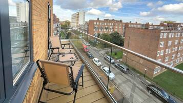 A balcony with chairs and a view of a street with cars and buildings.