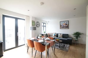 A modern living room with a dining area, a sofa, a coffee table, and a large window.