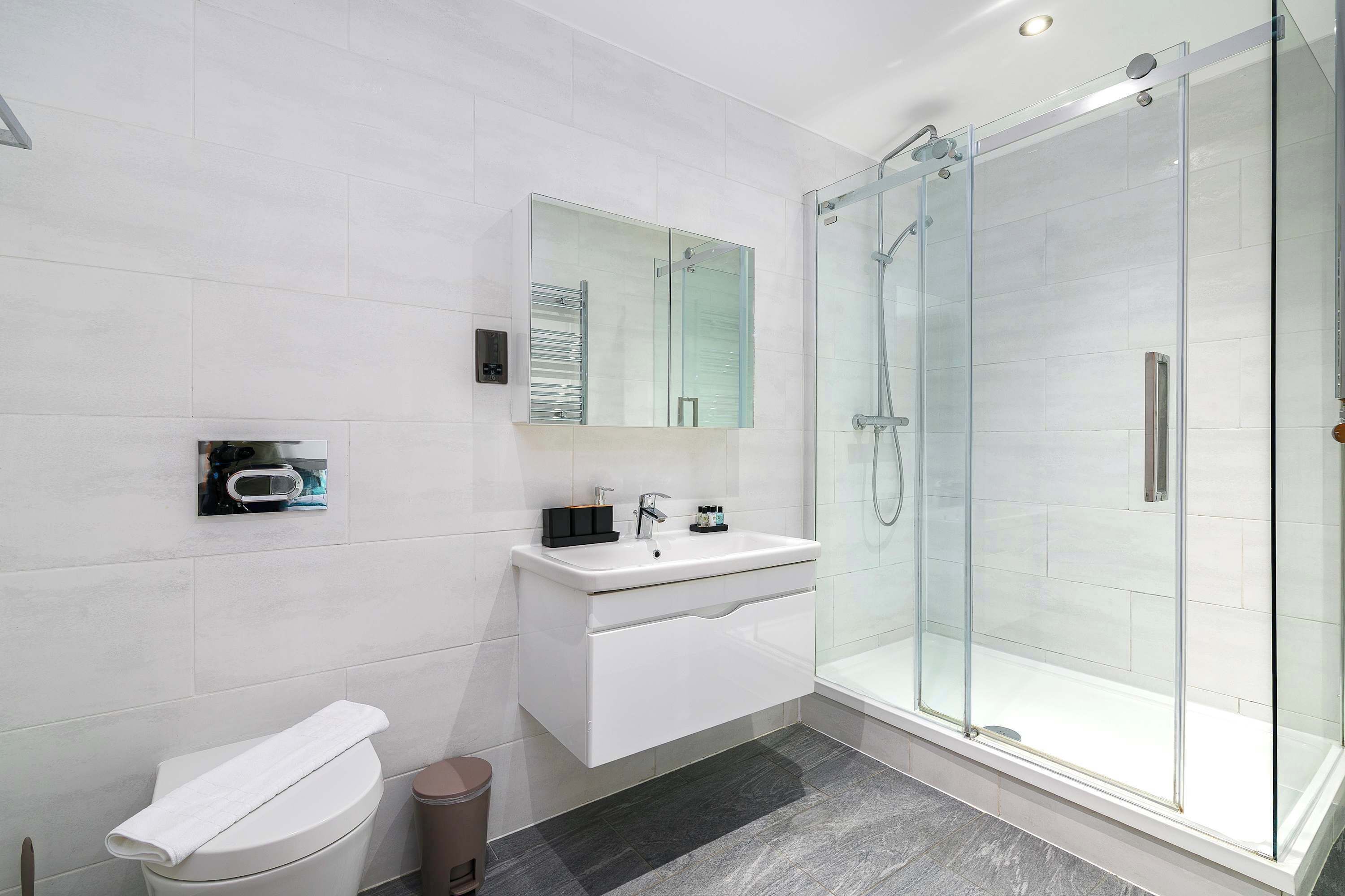 A modern bathroom with a glass-enclosed shower, a white sink, and a toilet.
