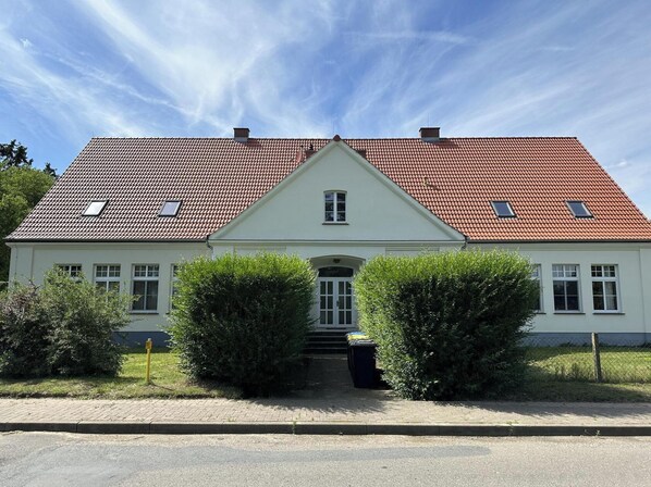 A two-story house with a red-tiled roof, white walls, and a central entrance with a small porch. - Fantastic country house villa! (Feldberger Seenlandschaft)