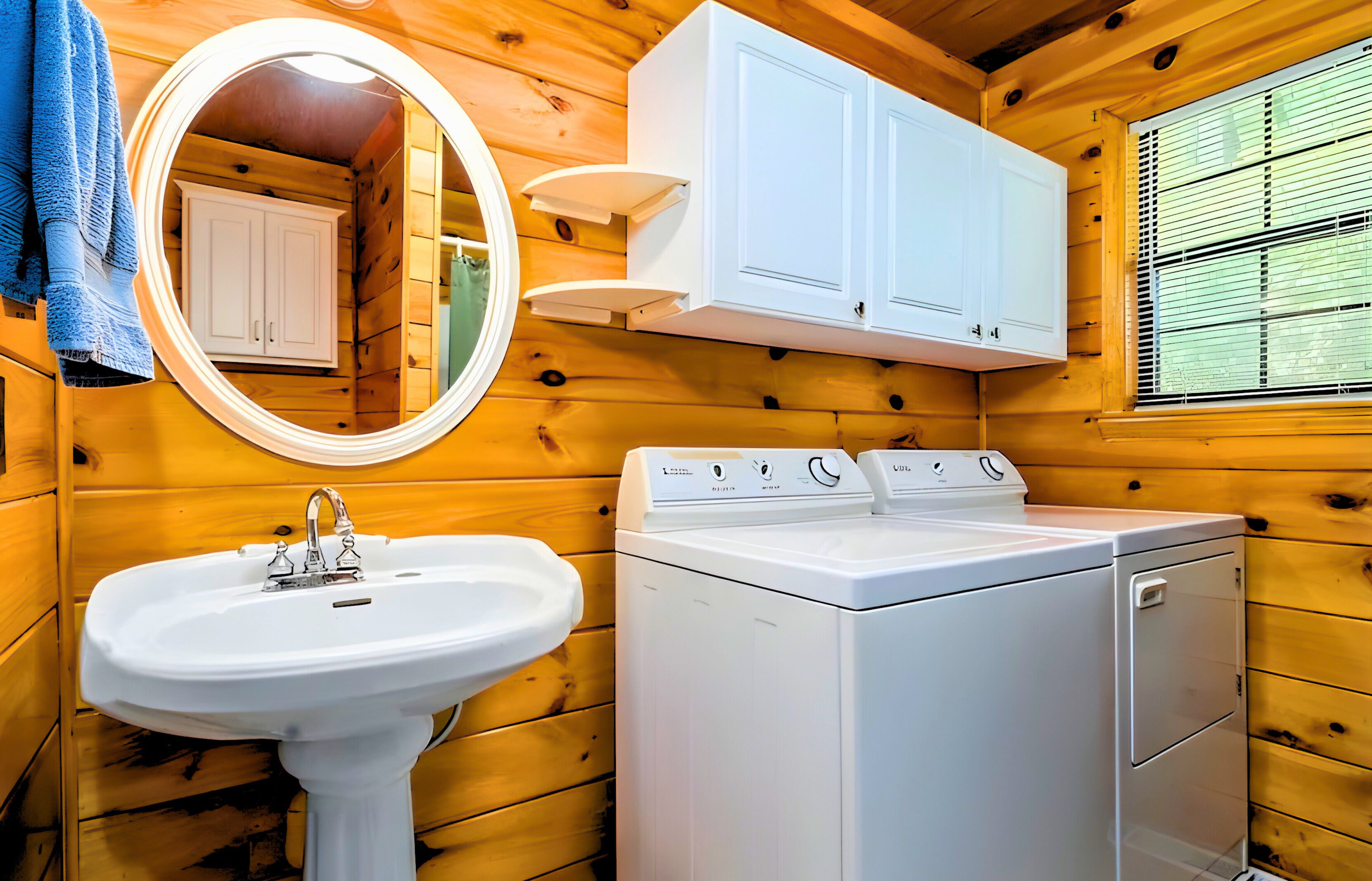 Une salle de bain rustique, située dans une cabane en bois, comprenant un lavabo, un miroir, un meuble de rangement et un lave-linge.