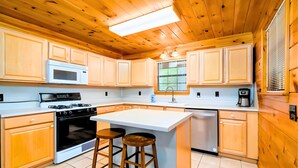 A kitchen with wooden cabinets, a microwave, a stove, and a sink. - Private Ellijay Cabin Sleeps 6 - Loft, Stone Fireplace, Trails & Lake Nearby (Ellijay)