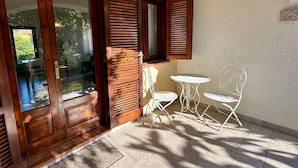A patio with a wooden door, a small table, and two chairs. - Villetta Oasi La Cinta Centro (San Teodoro)