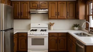 A kitchen with wooden cabinets, a stainless steel refrigerator, a white stove, and a sink. - Welcome to your perfect city retreat in the heart of Skokie! (Skokie)