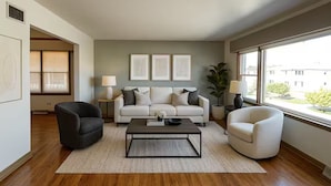 A modern living room with a sofa, two armchairs, a coffee table, and a large window offering a view of the outside. - Welcome to your perfect city retreat in the heart of Skokie! (Skokie)