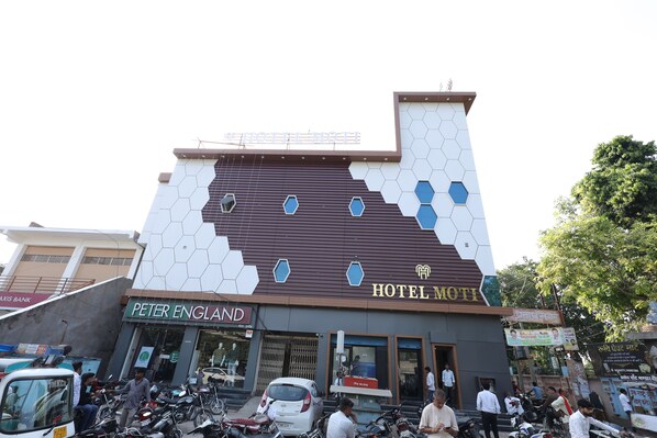 A building with a sign for 'Hotel Moti' and 'Peter England' across the street.