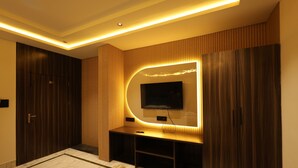 A modern living room with a built-in TV, wooden paneling, and a marble floor. - Hotel Moti (Mau Ranipur)