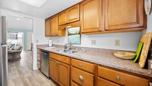 Una cocina con armarios de madera, encimeras de granito, lavavajillas y un lavabo.