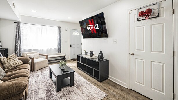 En moderne stue med sofa, sofabord og et TV på væggen, der viser Netflix-logoet.