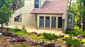 Une maison moderne avec un toit en pente, de grandes fenêtres et des fondations en pierre.
