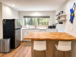 A modern kitchen with a wooden island, stainless steel appliances, and a view of the forest. - New -Treehouse Studio -Amazing Views -Easy Access (Flagstaff)