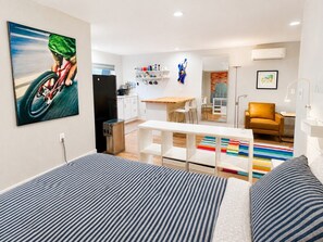 Une chambre d’hôtel moderne équipée d’un lit, d’un bureau, d’une chaise, d’un canapé et d’un coin cuisine.