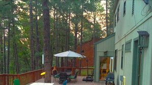 Une terrasse en bois aménagée avec du mobilier d’extérieur, notamment une table et des chaises, ainsi qu’un barbecue.