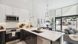 Una cocina moderna con una isla central, electrodomésticos de acero inoxidable e iluminación colgante.