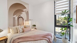 Un dormitorio con una cama grande, una planta en maceta y una ventana con persianas.