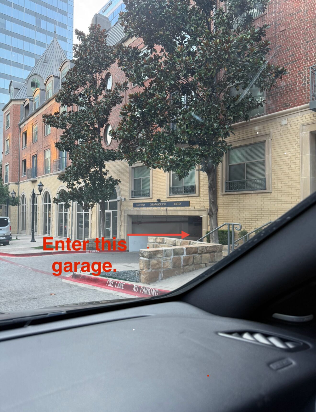A street view with a building labeled "EXIT ONLY CLEARANCE 6'8" ENTRY" and a sign indicating "Enter this garage."