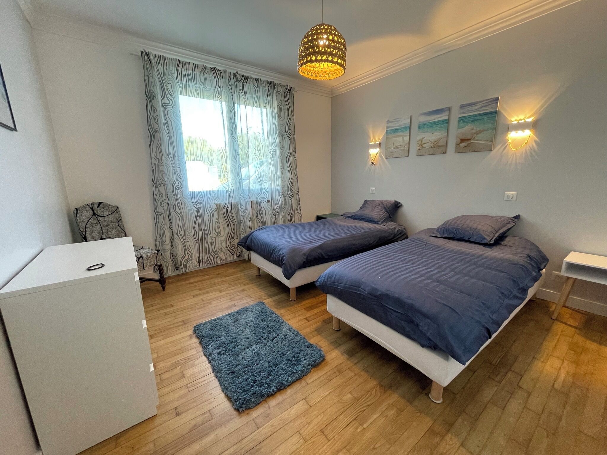 Ein Schlafzimmer mit zwei Betten, einem Schreibtisch, einem Stuhl, einem Teppich und einem Fenster mit Vorhängen.