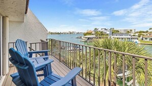 A balcony with blue Adirondack chairs overlooking a marina with boats and a dock.