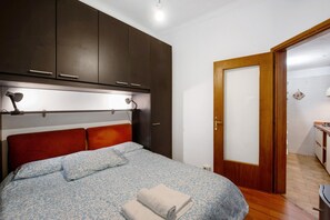 A bedroom with a bed, wooden wardrobe, and a door leading to a bathroom.