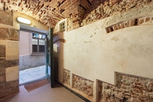A corridor with stone walls, a door, and a tiled floor.